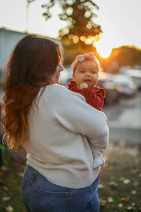 a woman holding a baby in her arms at sunset