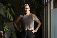 a woman with tattoos standing in front of a window