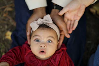 a baby is being held up by a person in a red dress
