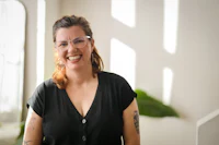 a woman with tattoos smiling in front of a window