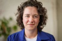 a woman with curly hair in a blue jacket