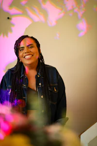 a woman with dreadlocks smiling in front of a colorful background