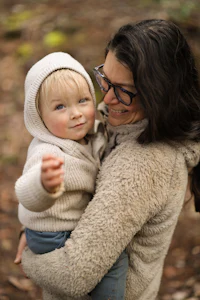 a woman holding a child in the woods