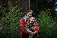 two women hugging in front of a tree