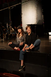 two women sitting on a stage