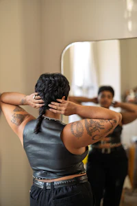 a woman putting her hair up in front of a mirror