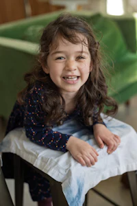 a little girl sitting on a high chair