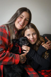 a woman and her daughter with a black and white dog