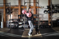 a woman with a dog standing in a gym