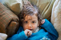 a young child laying on a couch with stuffed animals