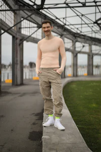 a man in a pink sweater standing on a concrete wall