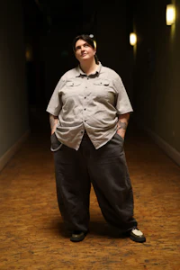 a woman in a gray shirt standing in a hallway