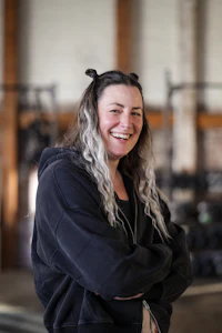 a woman in a black hoodie standing in a gym