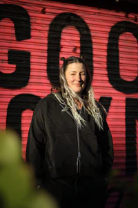 a woman in a black hoodie standing in front of a sign that says goodbye